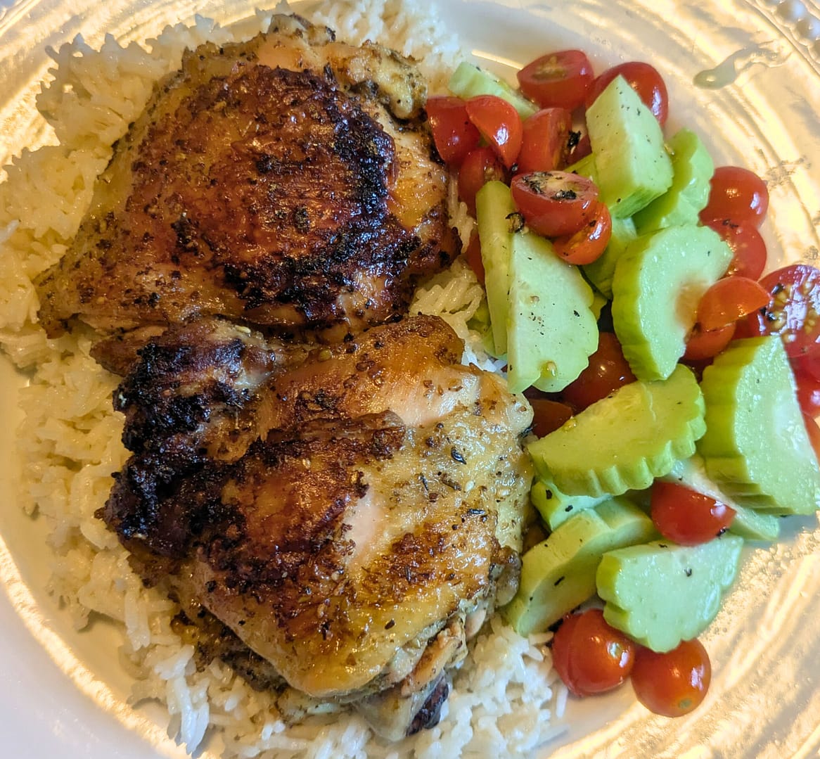 Picture of Lemon Chicken Thighs with creamy coconut rice and a cucumber tomato salad.